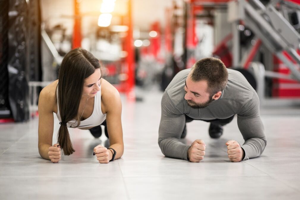 Un home e unha muller realizan o exercicio Plank, pensado para todos os grupos musculares